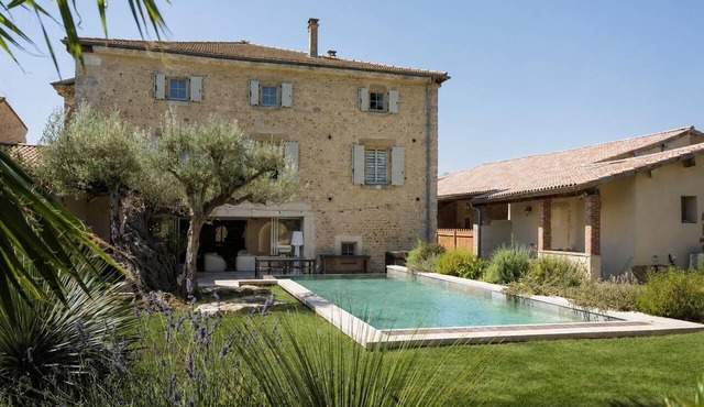 A magnificent stone mansion with a large swimming pool and a hot tub.